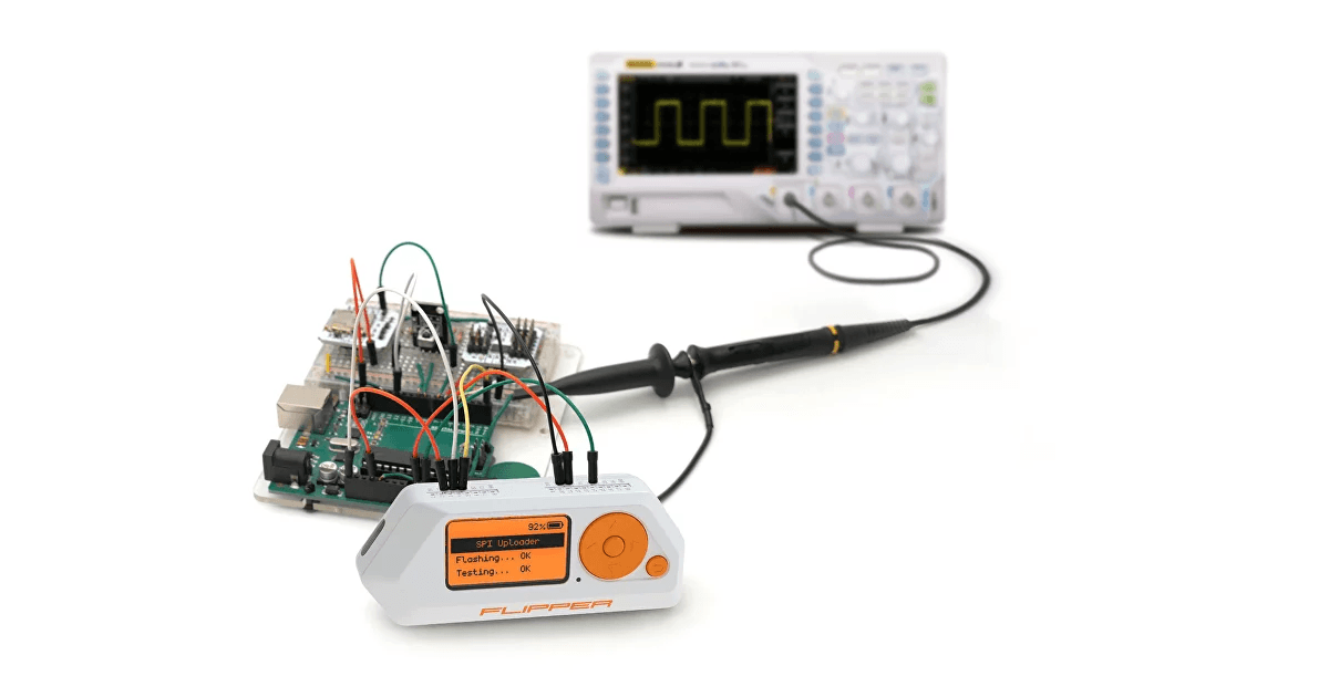 A Flipper Zero wired to a circuit board, with an oscilloscope probe showing a square wave