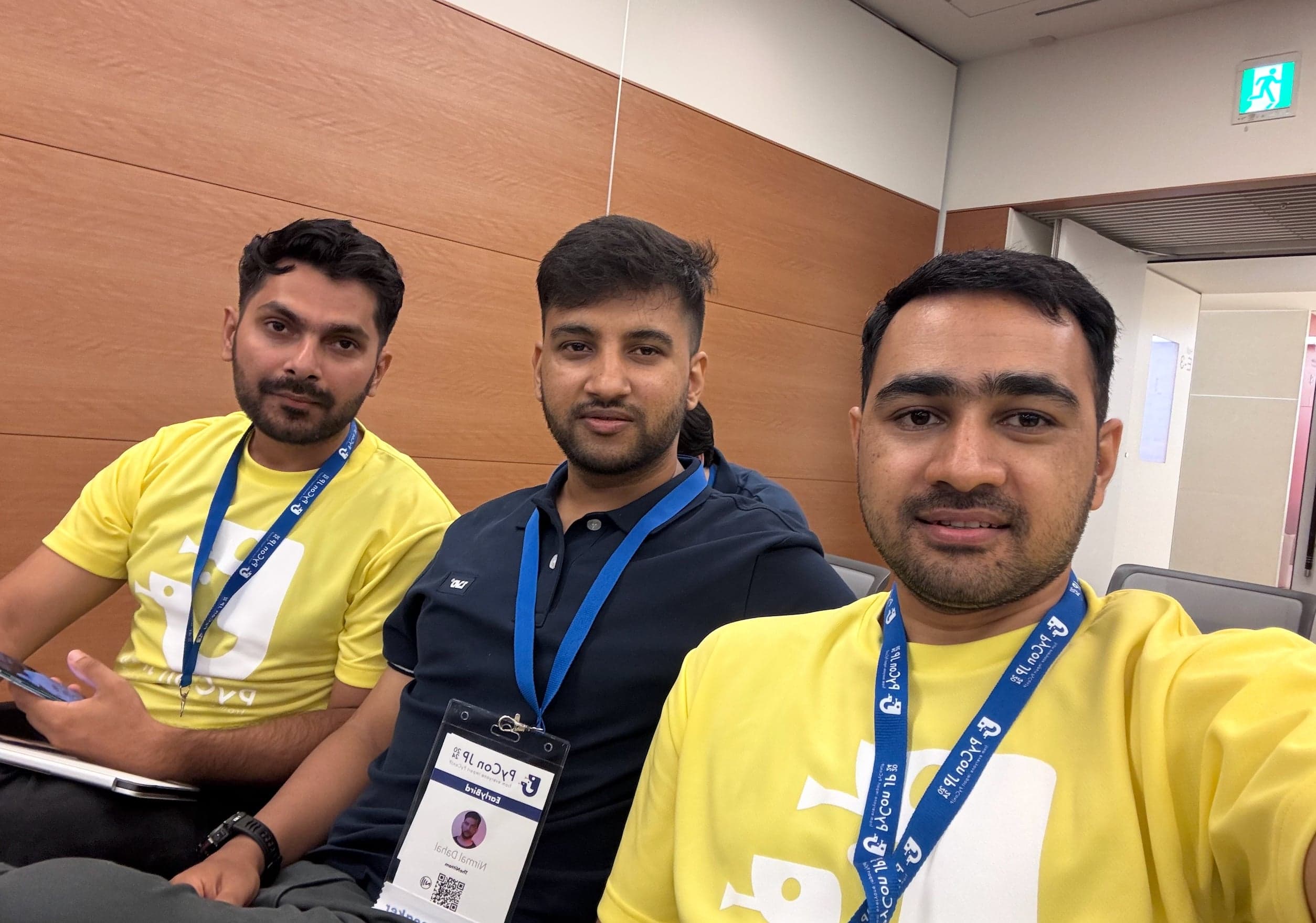 Selfie of Nirmal with two companions, two wearing yellow PyCon JP volunteer shirts and conference lanyards