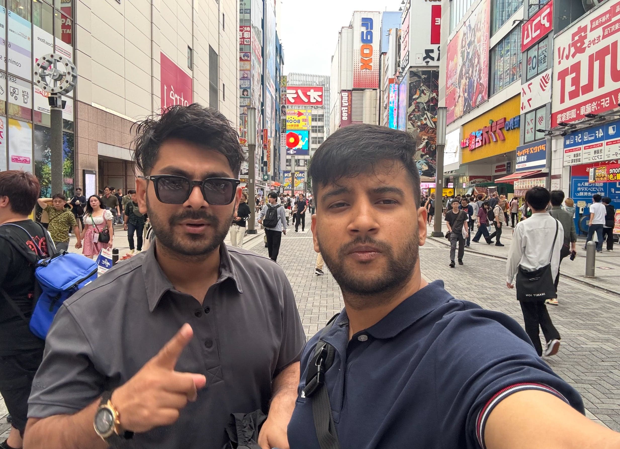 Nirmal and Robin Panthee taking a selfie on a busy Tokyo shopping street